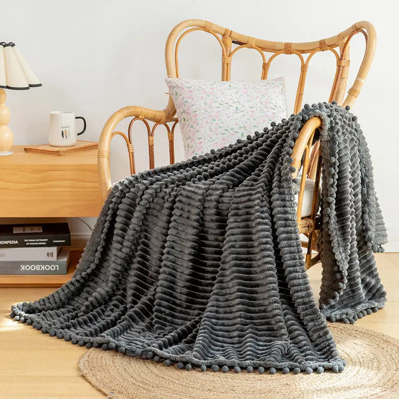 Velvet pom blanket with flannel texture offering lightweight comfort for home styling