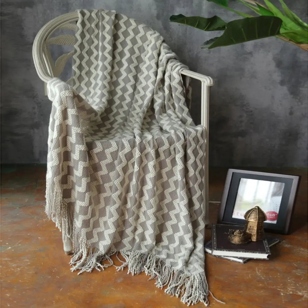 Soft geometric chenille throw with tassel trim draped over furniture for cozy styling