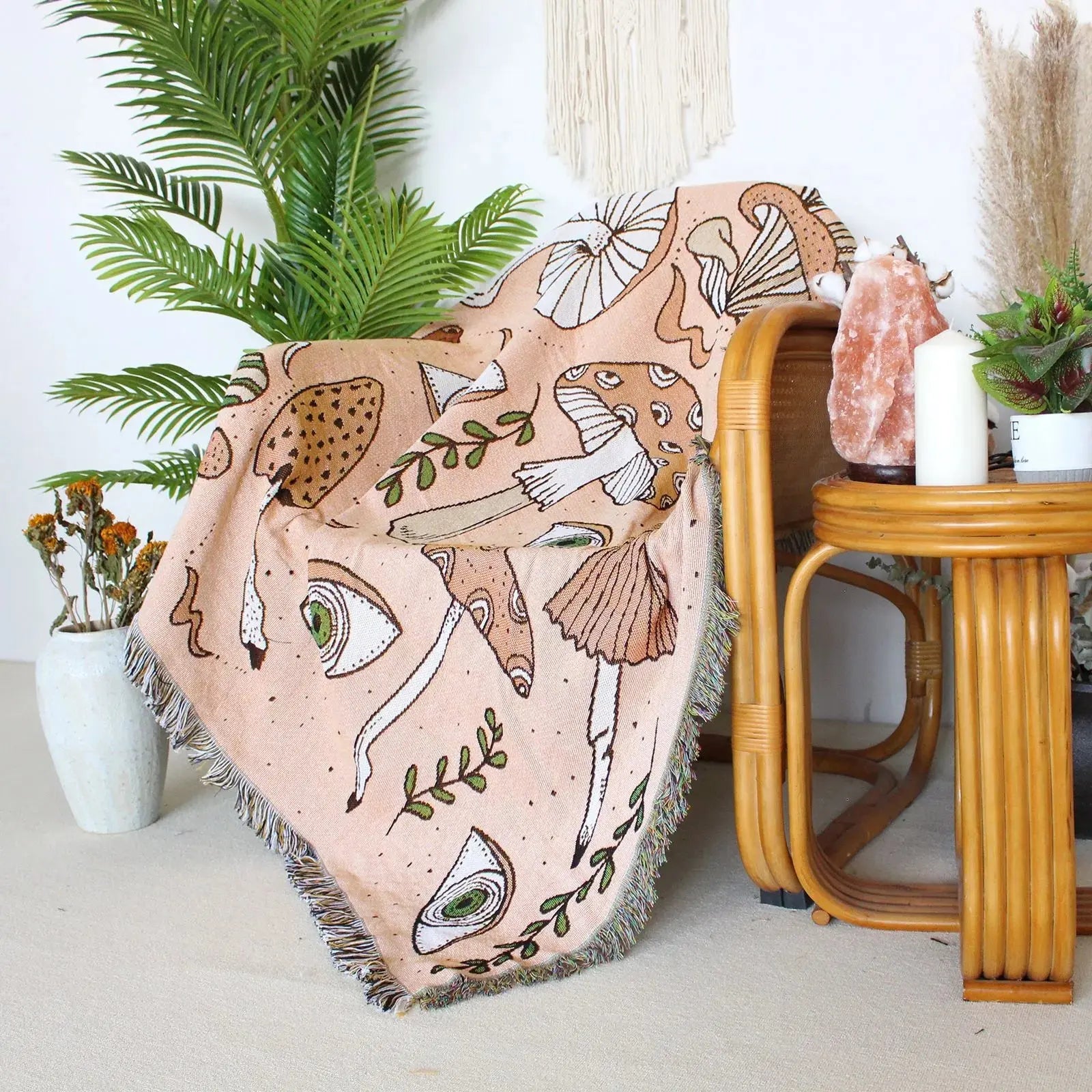 Decorative blanket with nature-themed design draped over a chair in a room with plants and a small table.