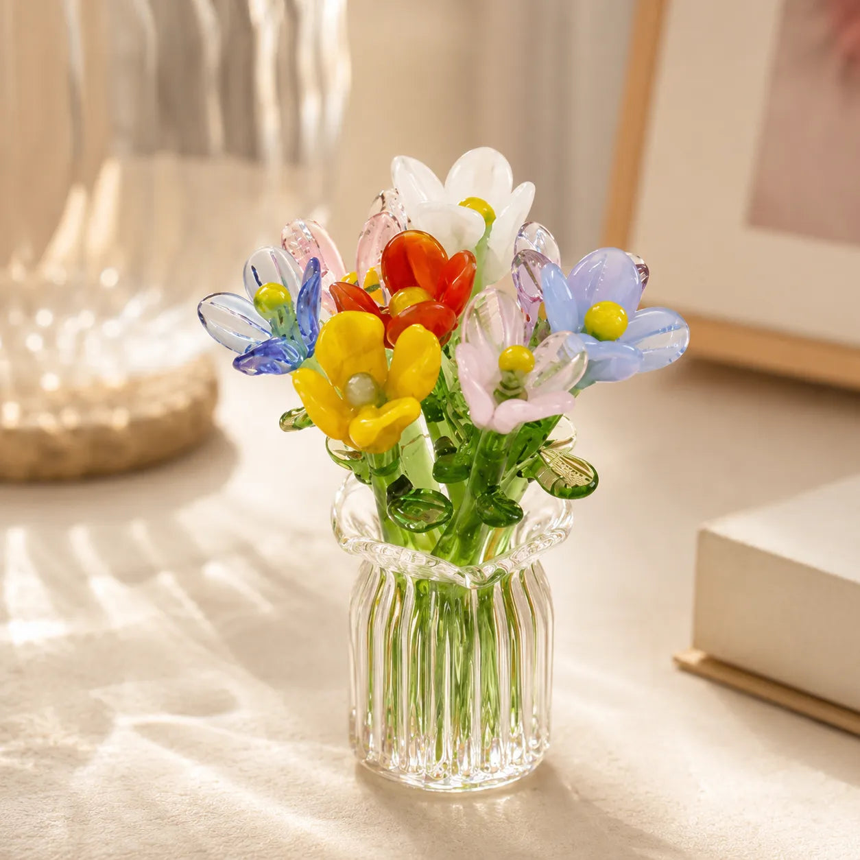 Clear glass vase with colorful artificial flowers on a light surface