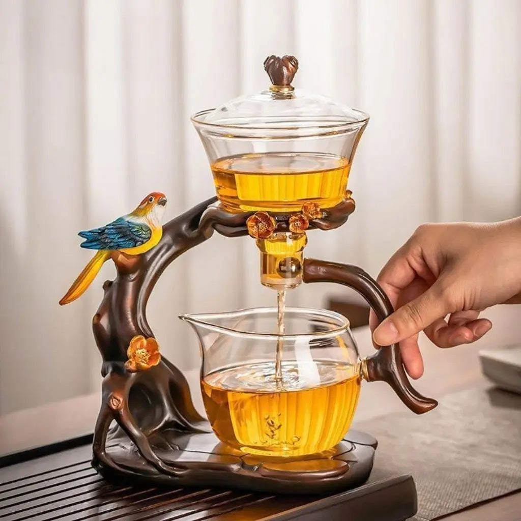 Tea-making apparatus with a decorative handle, filled with tea, on a neutral background.