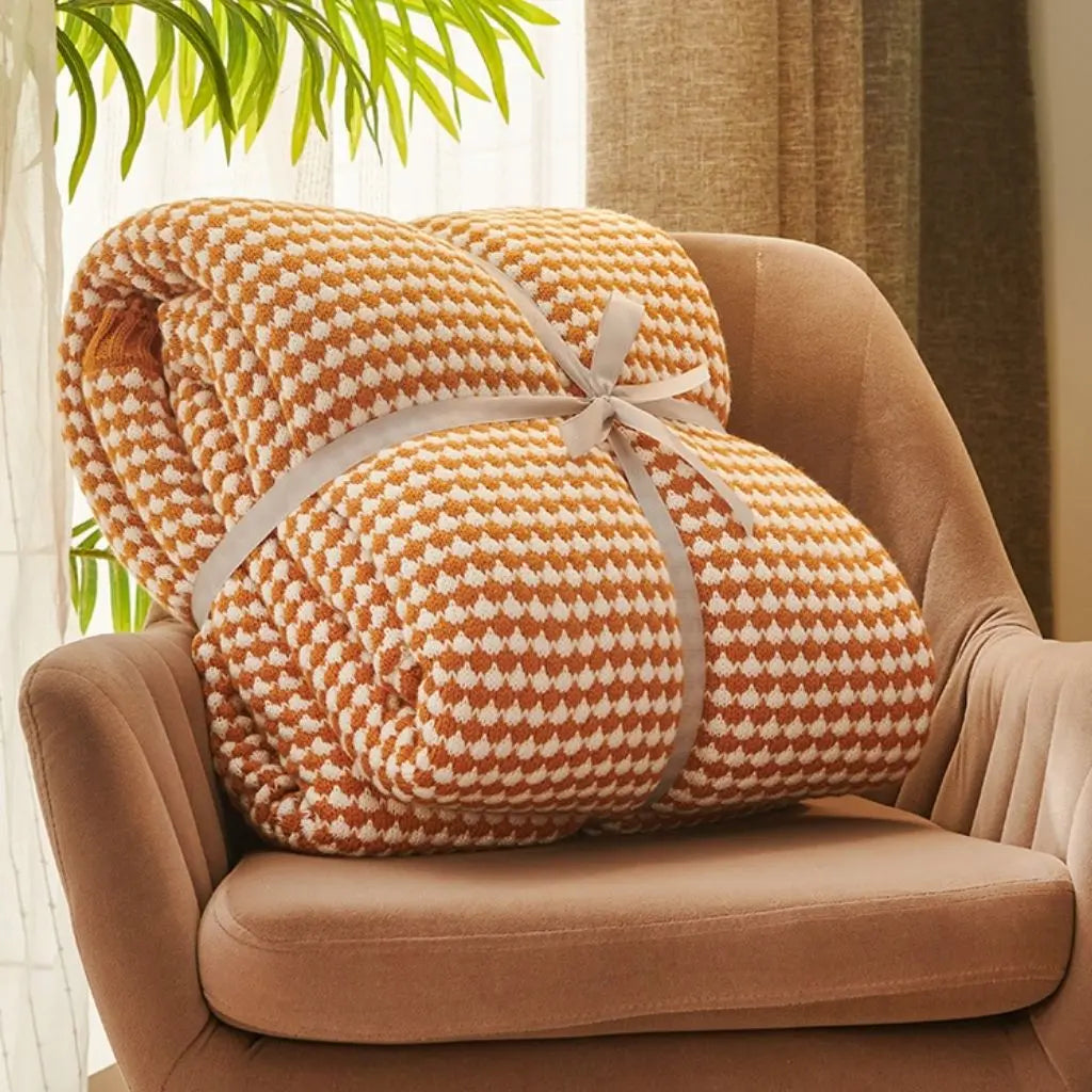 Jacquard patterned throw blanket layered on bed for decorative warmth and comfort