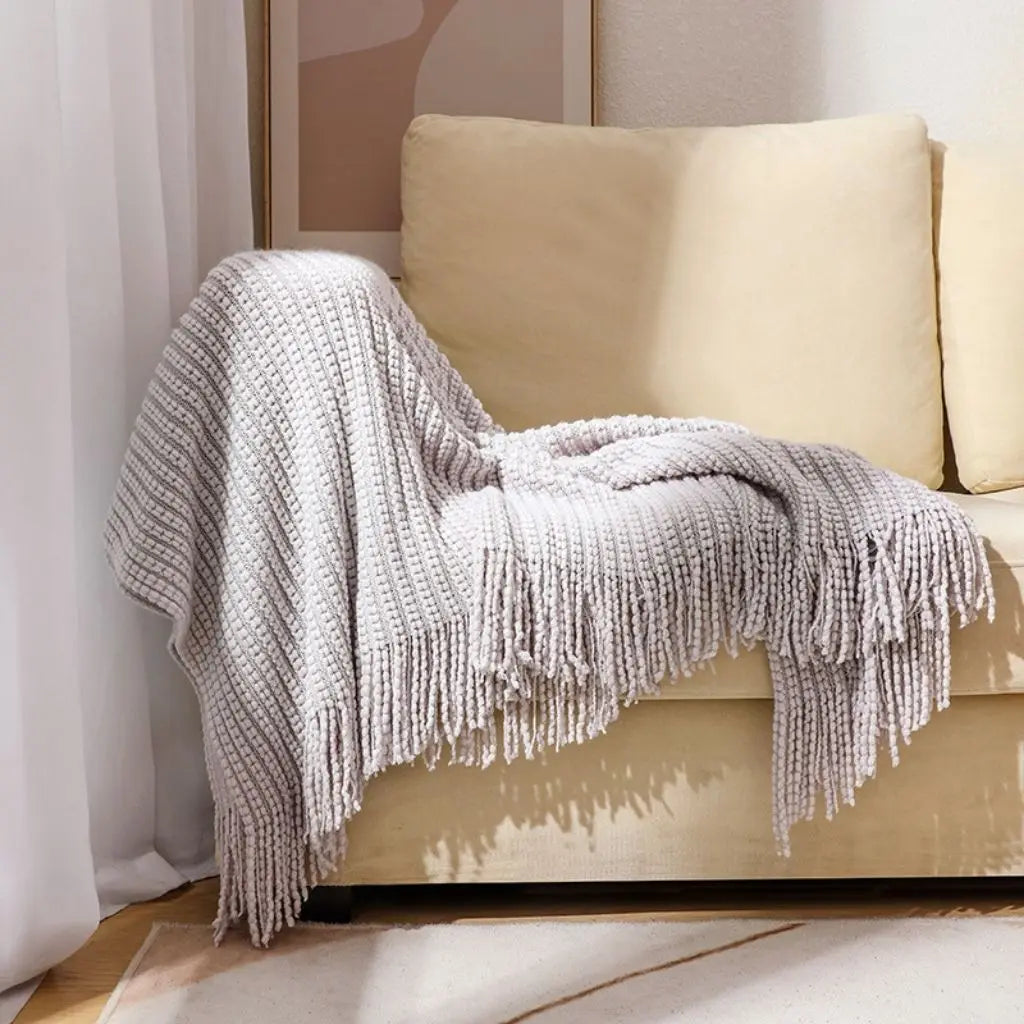 Woven chenille blanket with long fringe detailing offering rich tactile texture and warmth