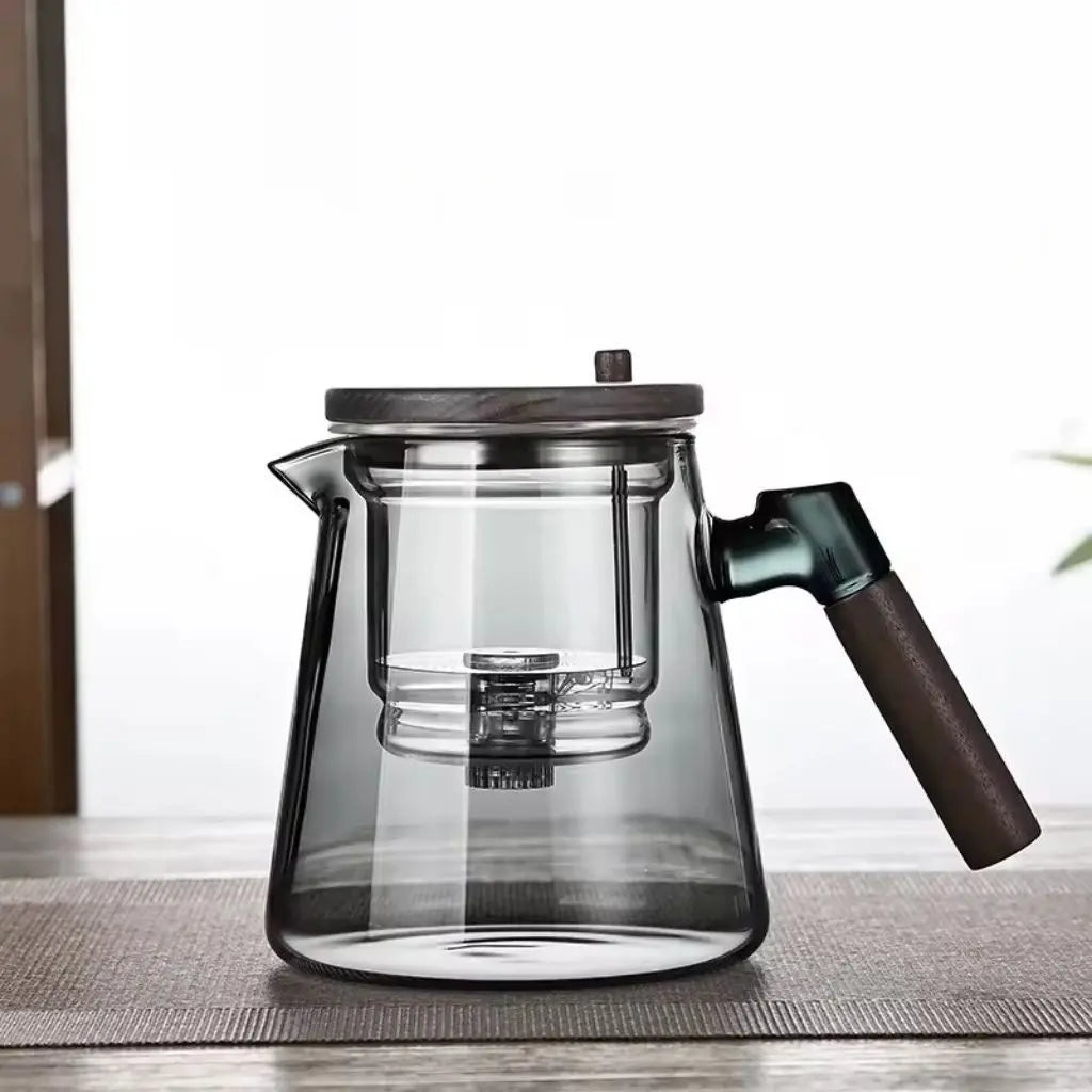 Clear glass coffee maker with wooden handle on a light wooden surface