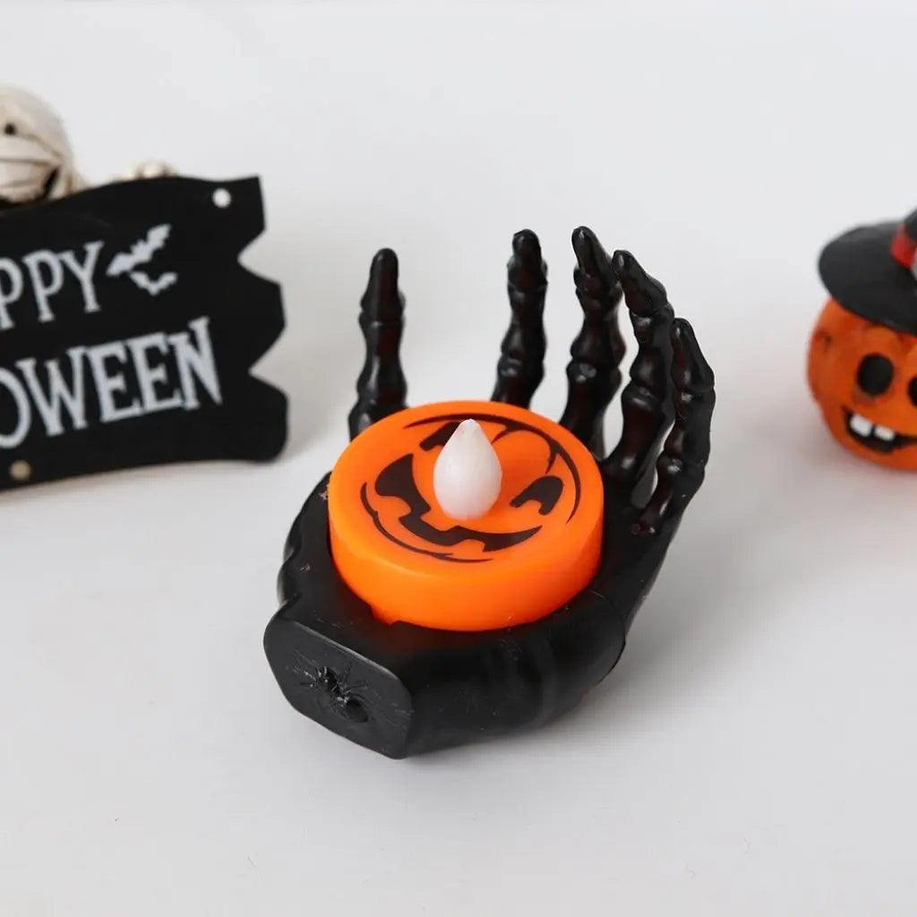 Halloween-themed LED candle light with a black hand holding an orange candle on a white background