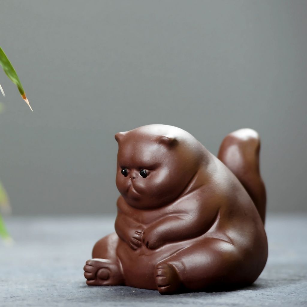 Angry cat tea pet made from purple clay featuring stern expression for tea ceremony rituals