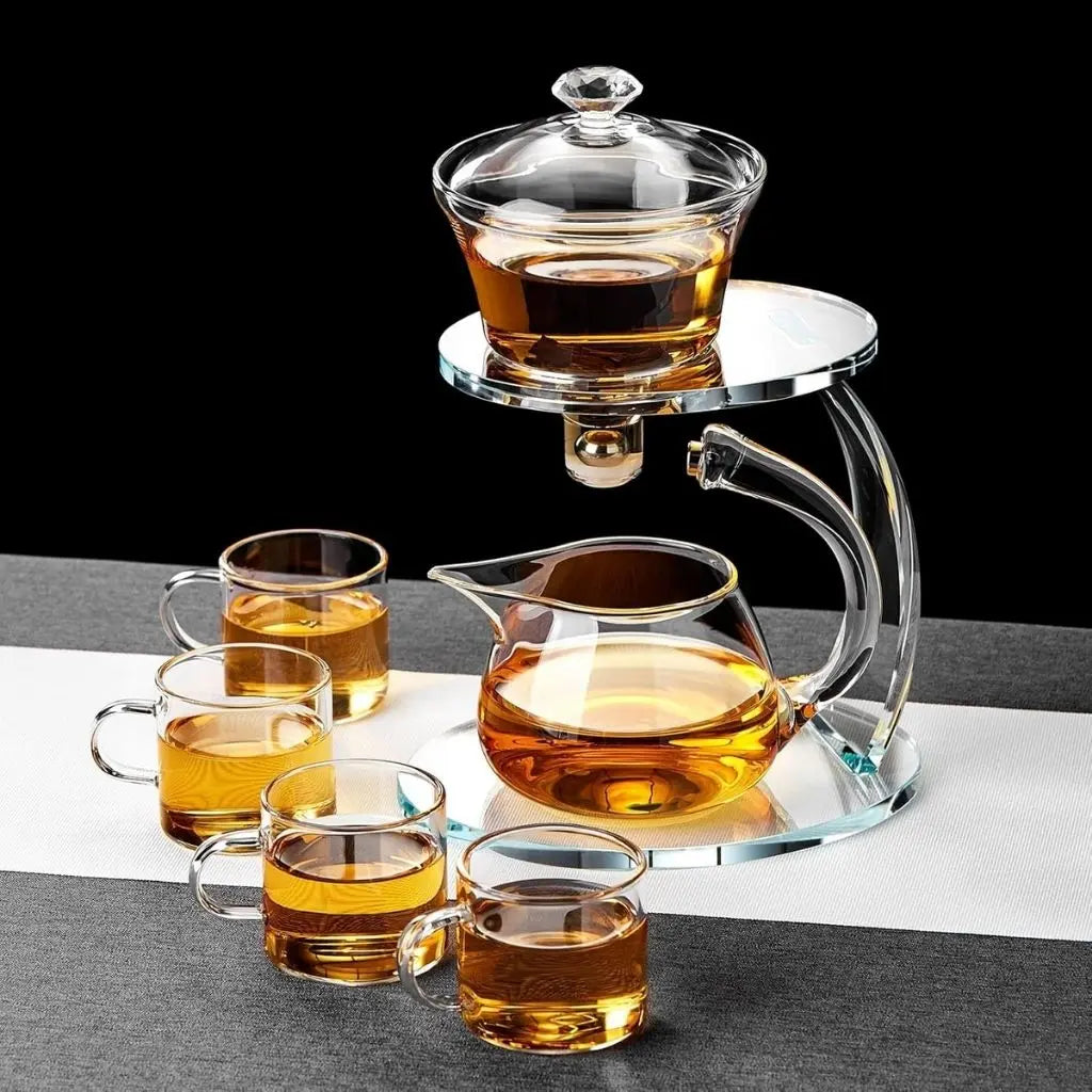Glass teapot and cups with tea on a black and white striped surface
