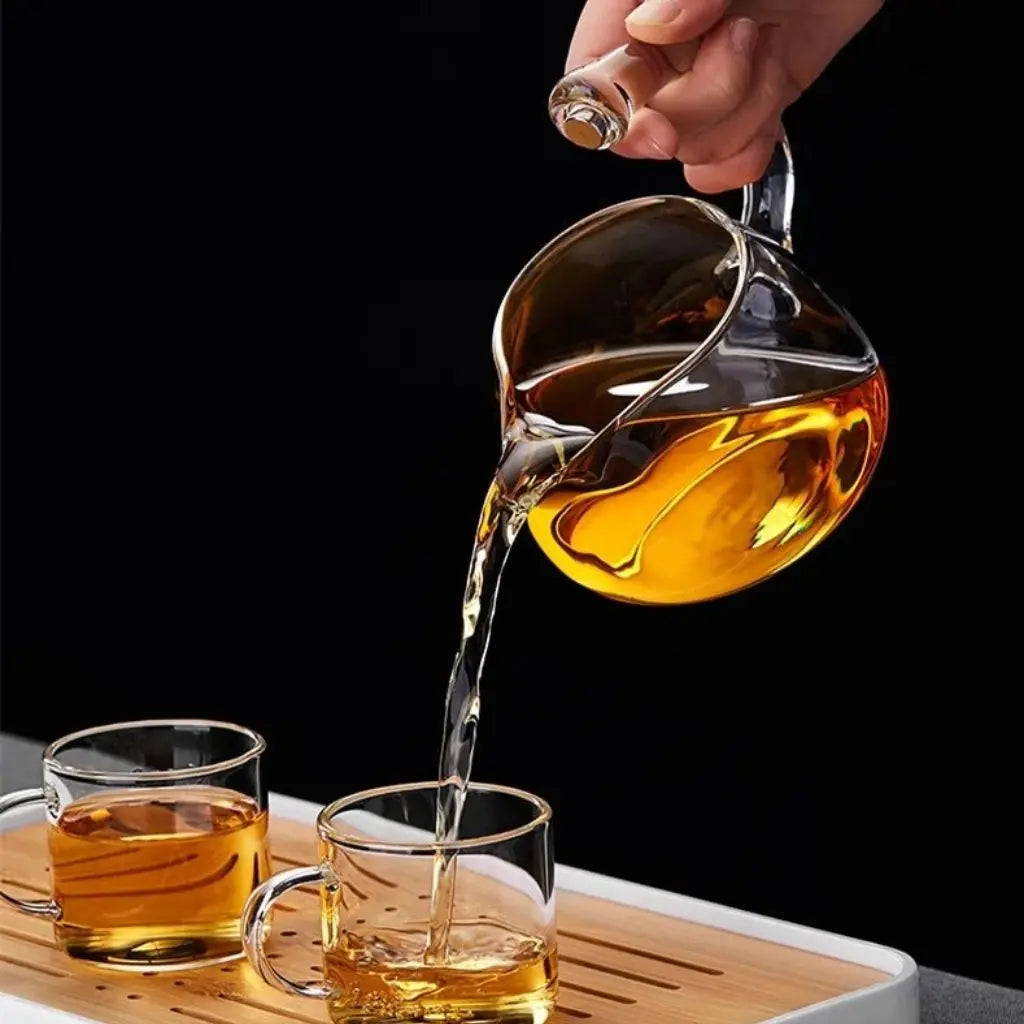 Glass decanter pouring liquid into two glasses on a wooden tray with a black background