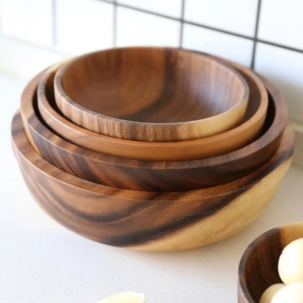 Set of three wooden bowls stacked on a light surface with a grid-patterned background