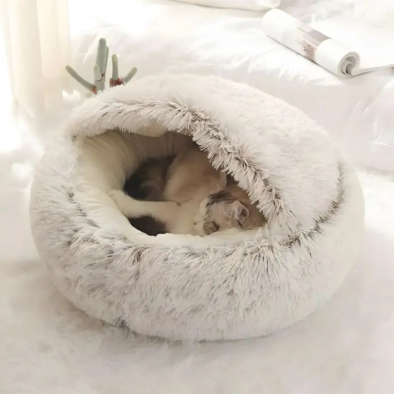 Cat sleeping in a fluffy white pet bed on a soft surface