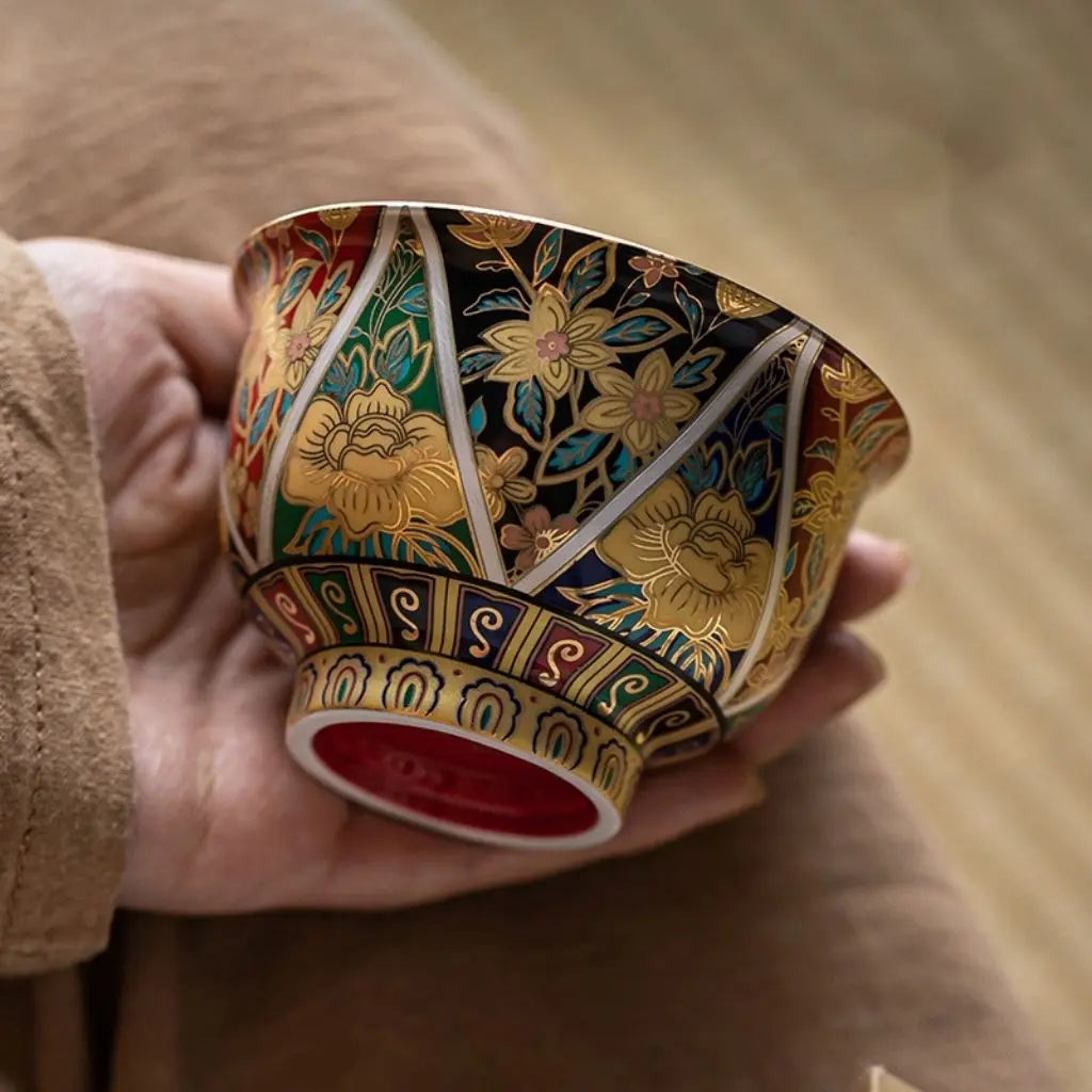Decorative ceramic cup with intricate patterns held in a hand against a blurred background