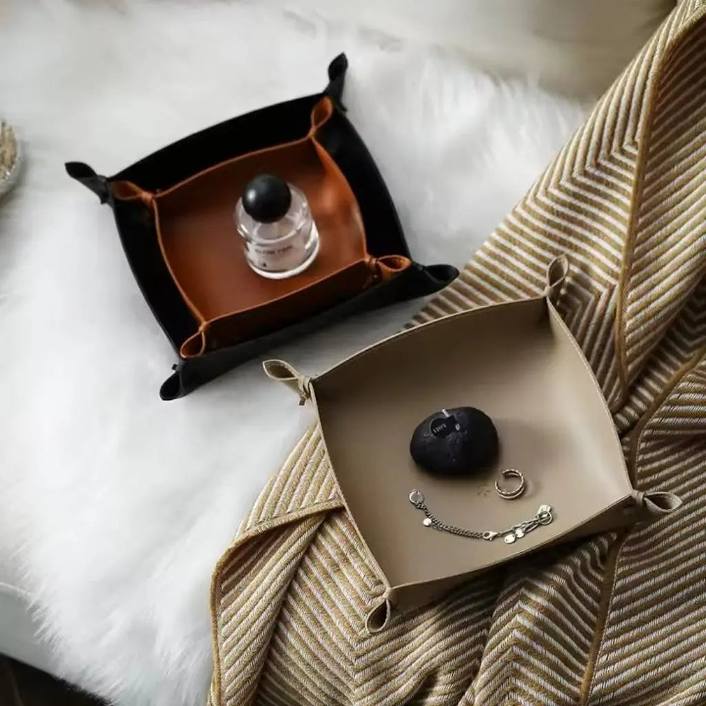 Collapsible leather storage tray with stitched edges and snap button corners for flat packing and travel