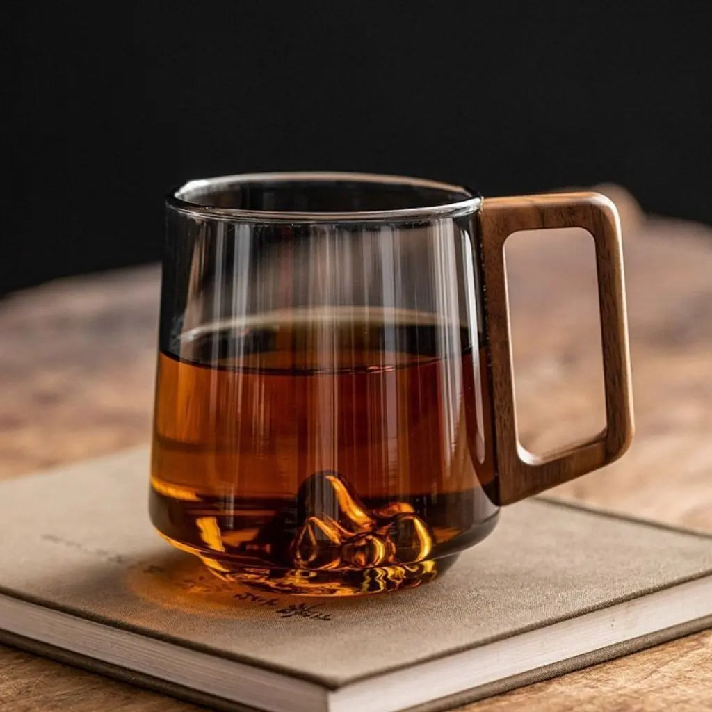 Borosilicate glass mug with wooden handle featuring mountain-shaped base in smoky green tone for hot beverages