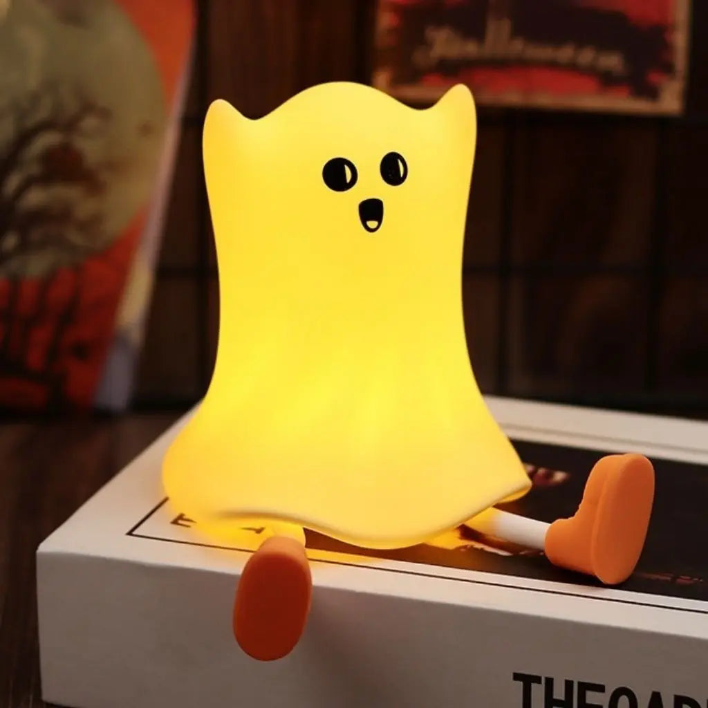 Yellow ghost toy with black eyes and orange shoes on a box
