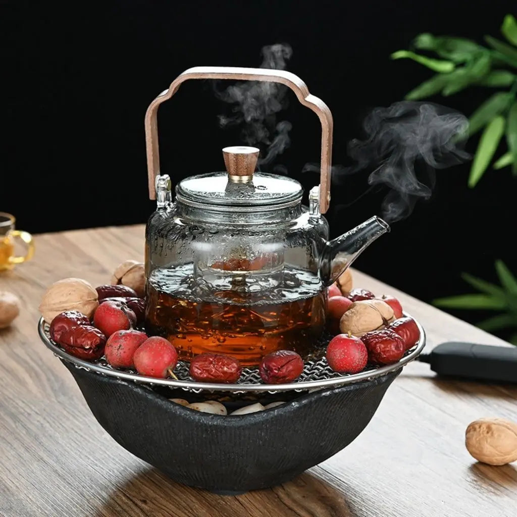 Glass teapot with steam on a wooden surface with fruits and nuts.