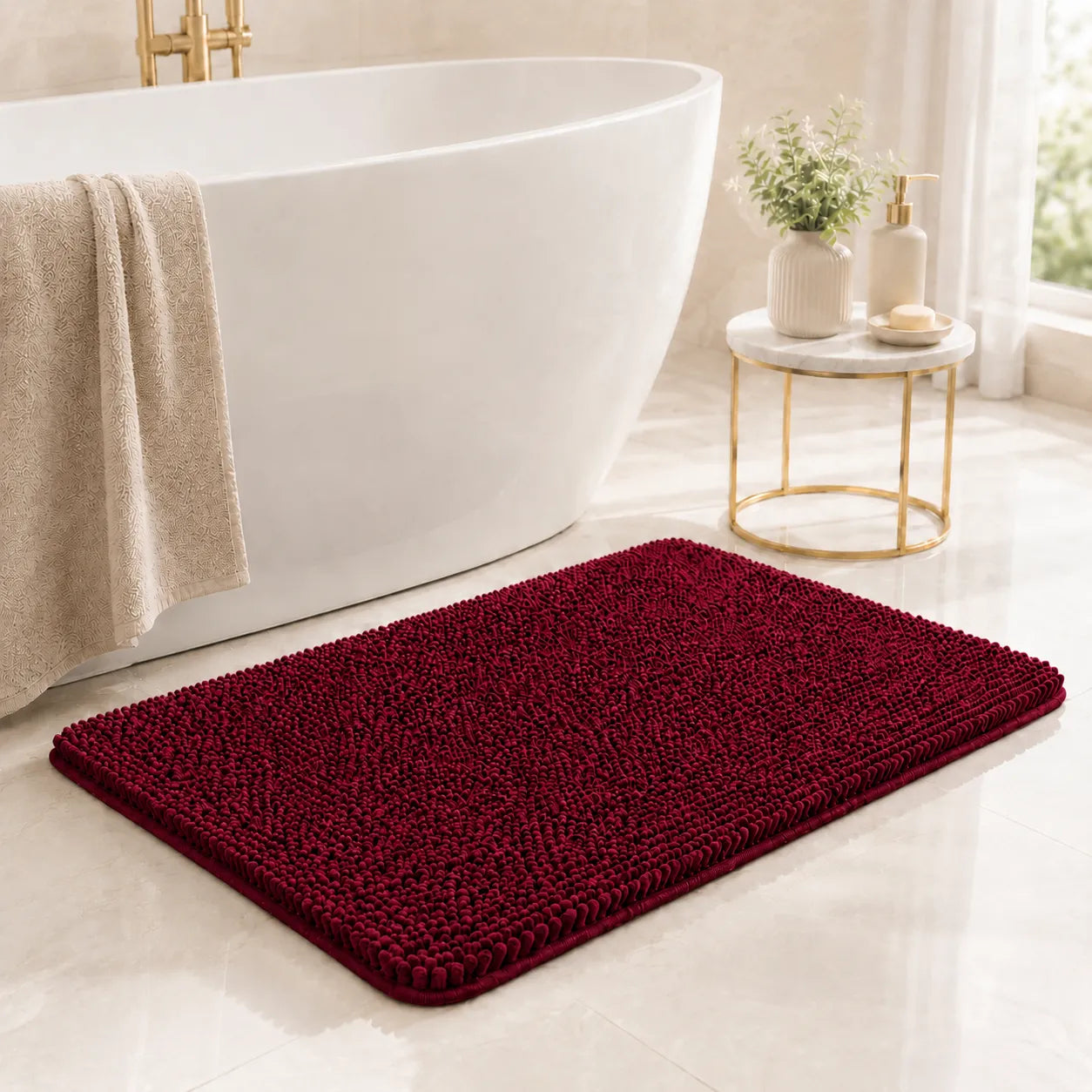 Red bath mat in front of a white bathtub with a small table and decorative items.