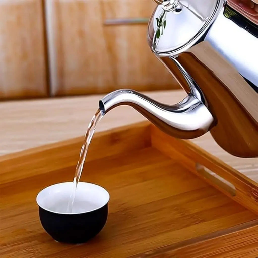 Teapot pouring water into a black and white cup on a wooden surface