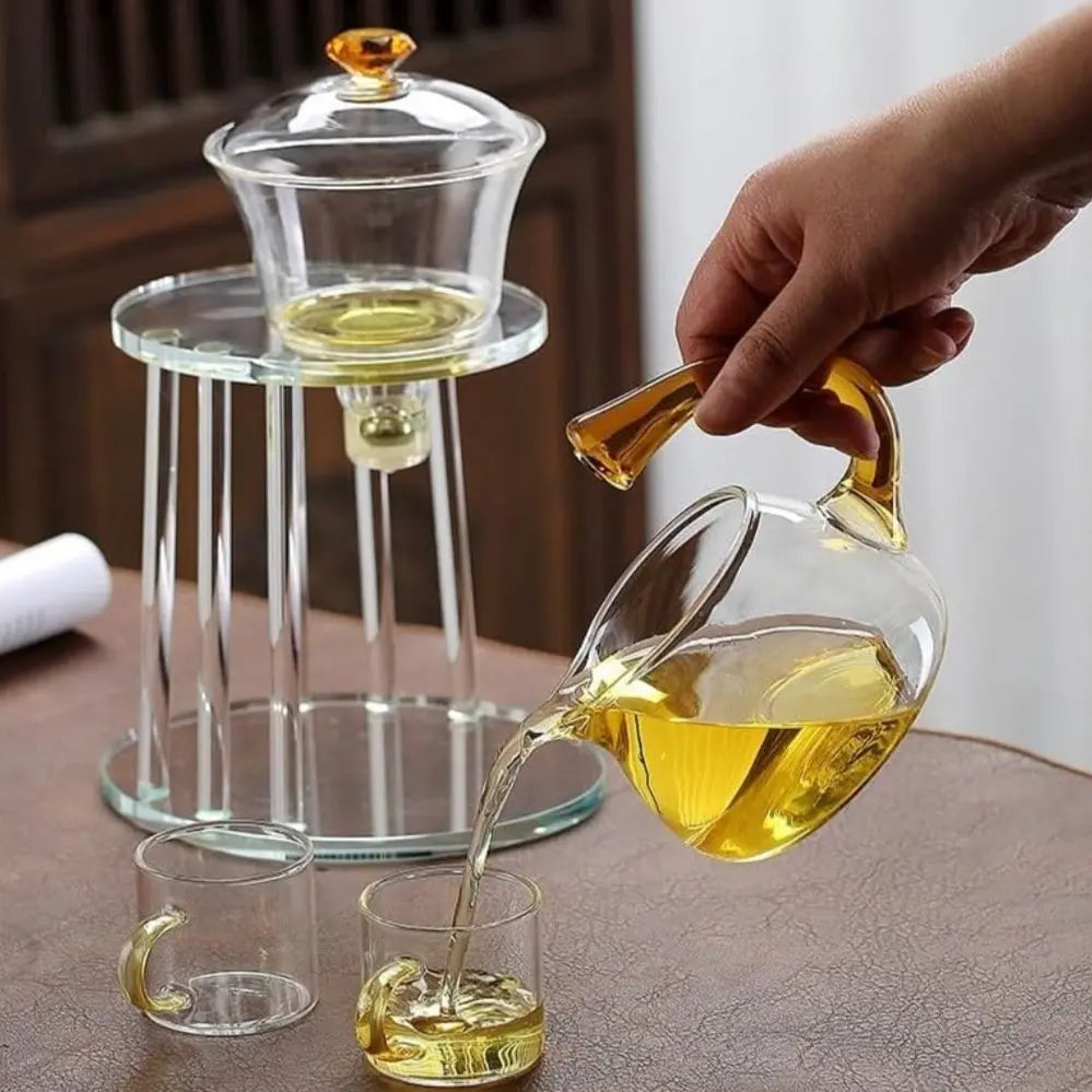 Pouring tea from a glass teapot into a glass on a wooden table.