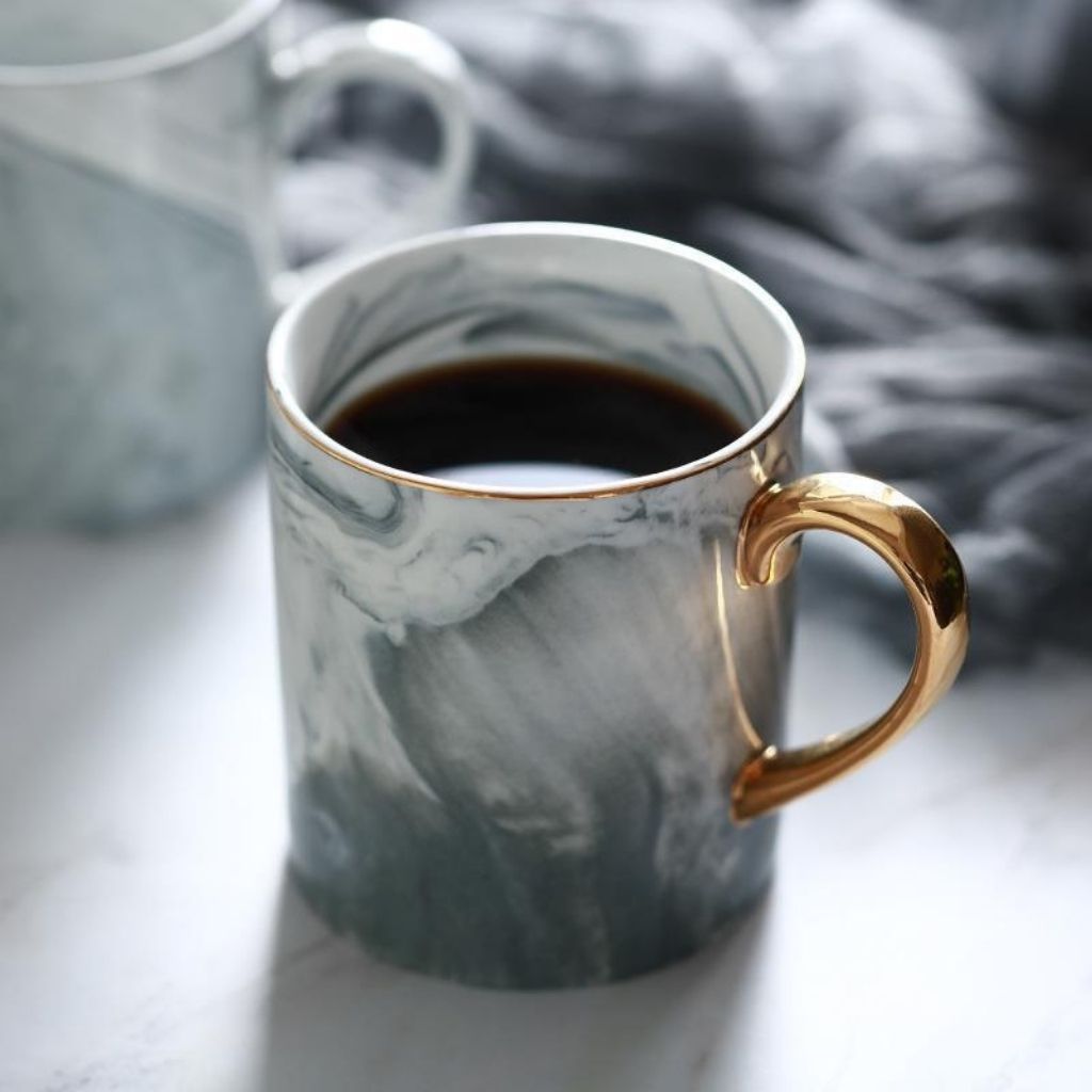 Ceramic marble mug with gold handle featuring gray pink marble pattern for coffee tea serving