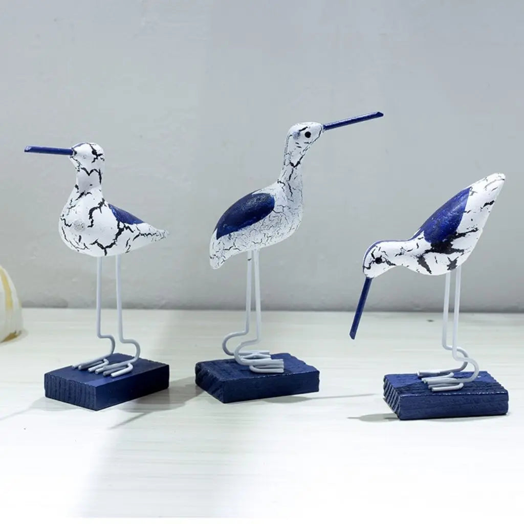 Three decorative bird figures on stands against a plain background