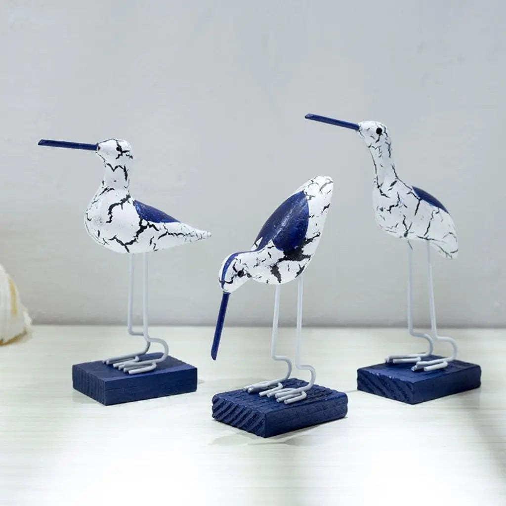 Three decorative bird figurines with blue and white marbled design on a light gray background.