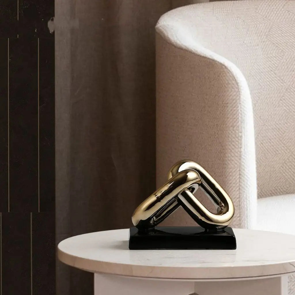 Gold metal sculpture on a black base on a round table with a neutral background