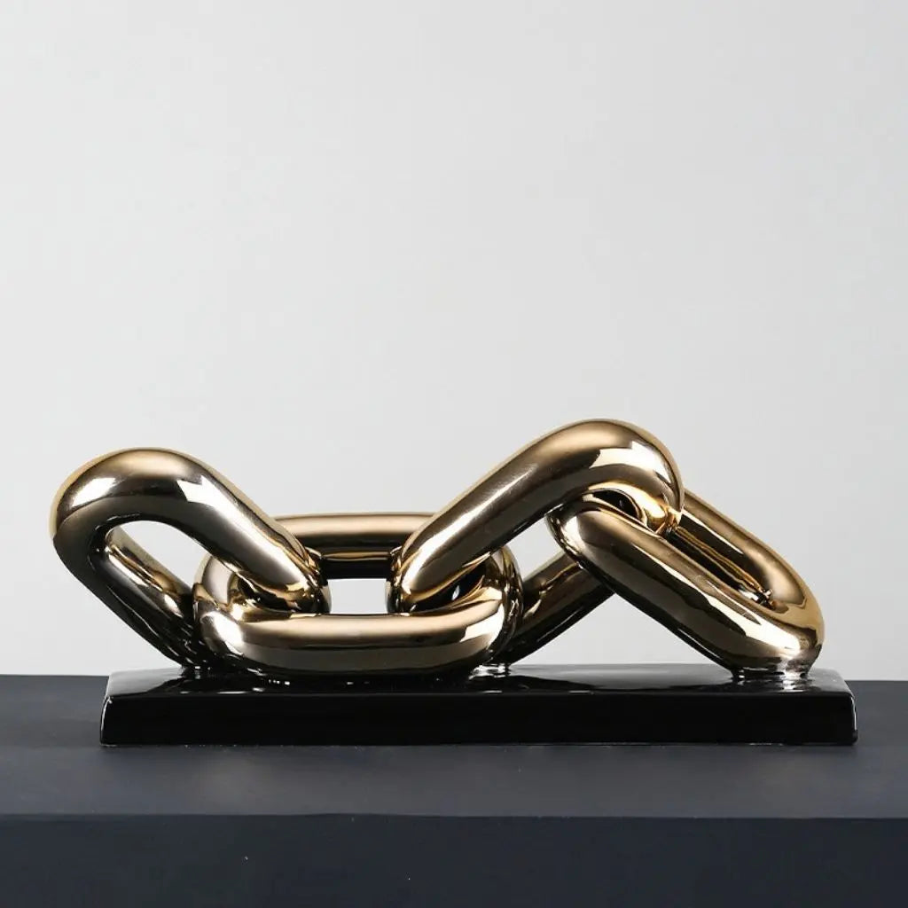 Gold chain sculpture on a black base against a gray background