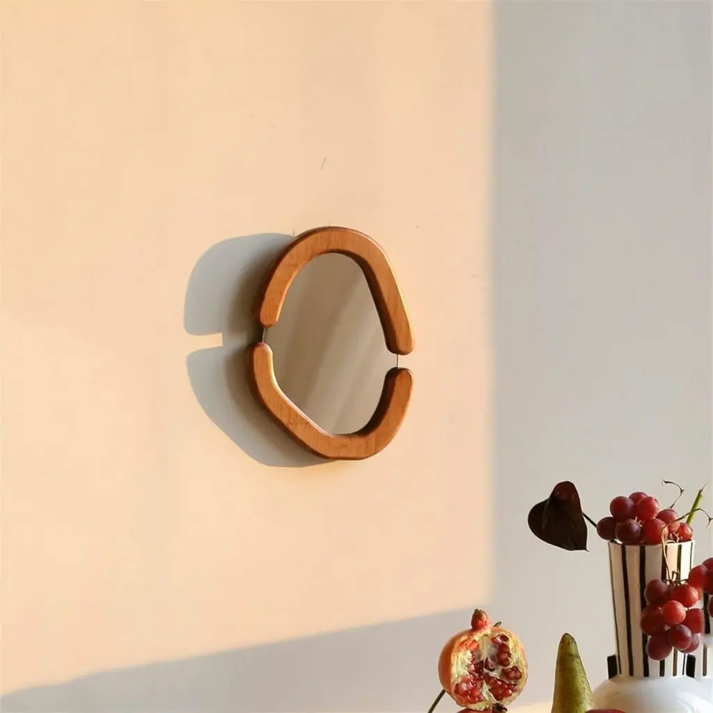 Decorative wall mirror with wooden frame on a light pink wall