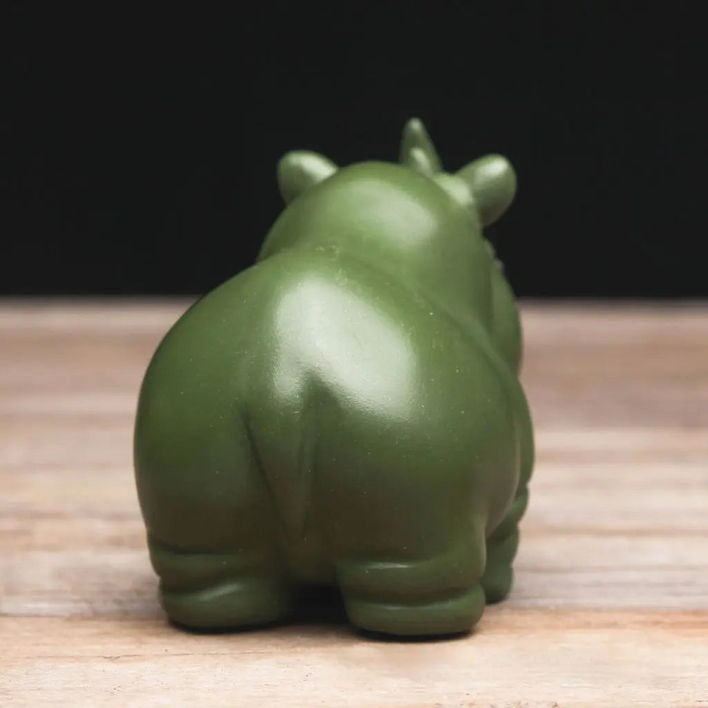 Green hippo figurine on a wooden surface with a dark background
