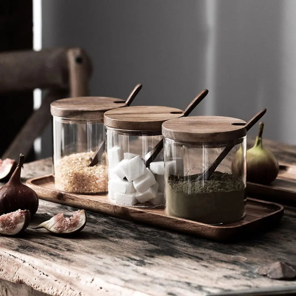 Clear glass storage jars with wooden tops for visible spice and herb organization.