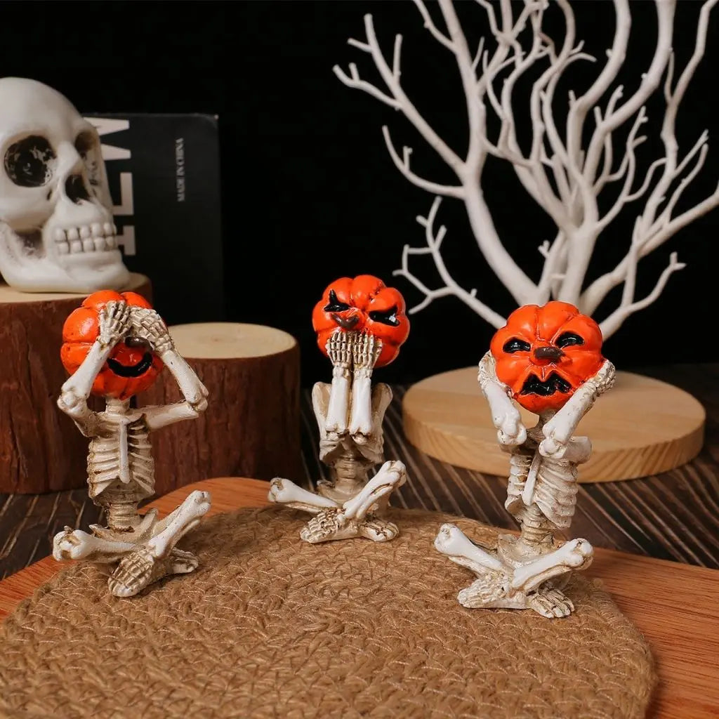 Halloween skull decorations with carved pumpkin heads in see no evil poses, resin skeleton ornaments for spooky decor