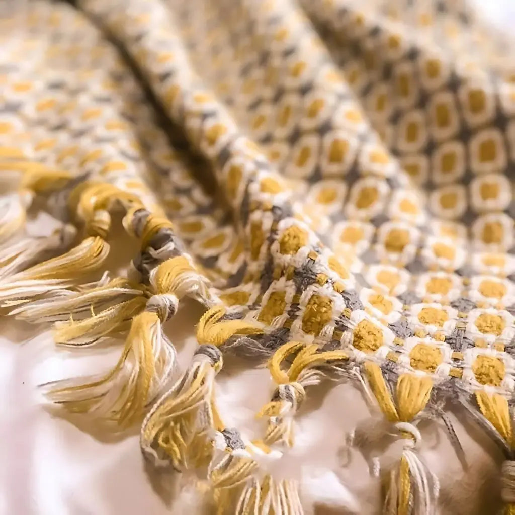 Close-up of knitted throw blanket featuring geometric pattern and handcrafted tassel edge details