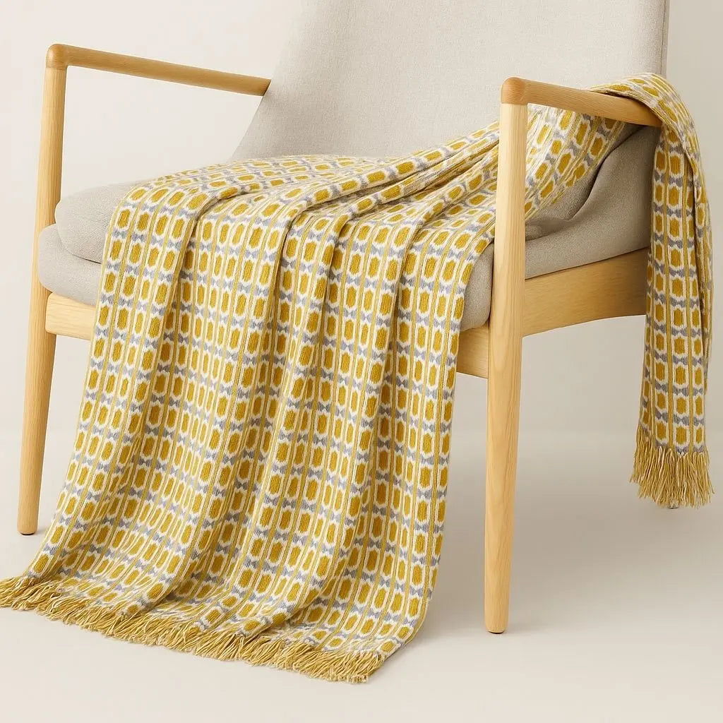 Yellow geometric blanket draped over sofa showcasing Nordic knitted texture and tasseled finish
