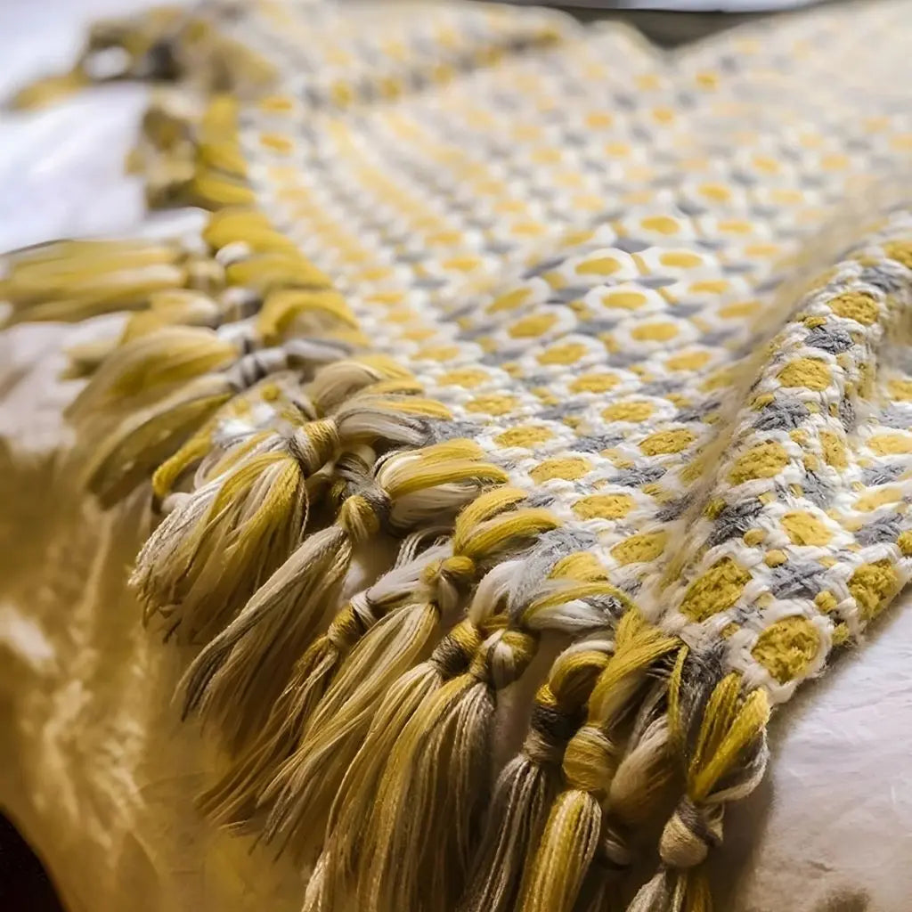 Soft knitted blanket with geometric Nordic design and decorative tassels for cozy home styling