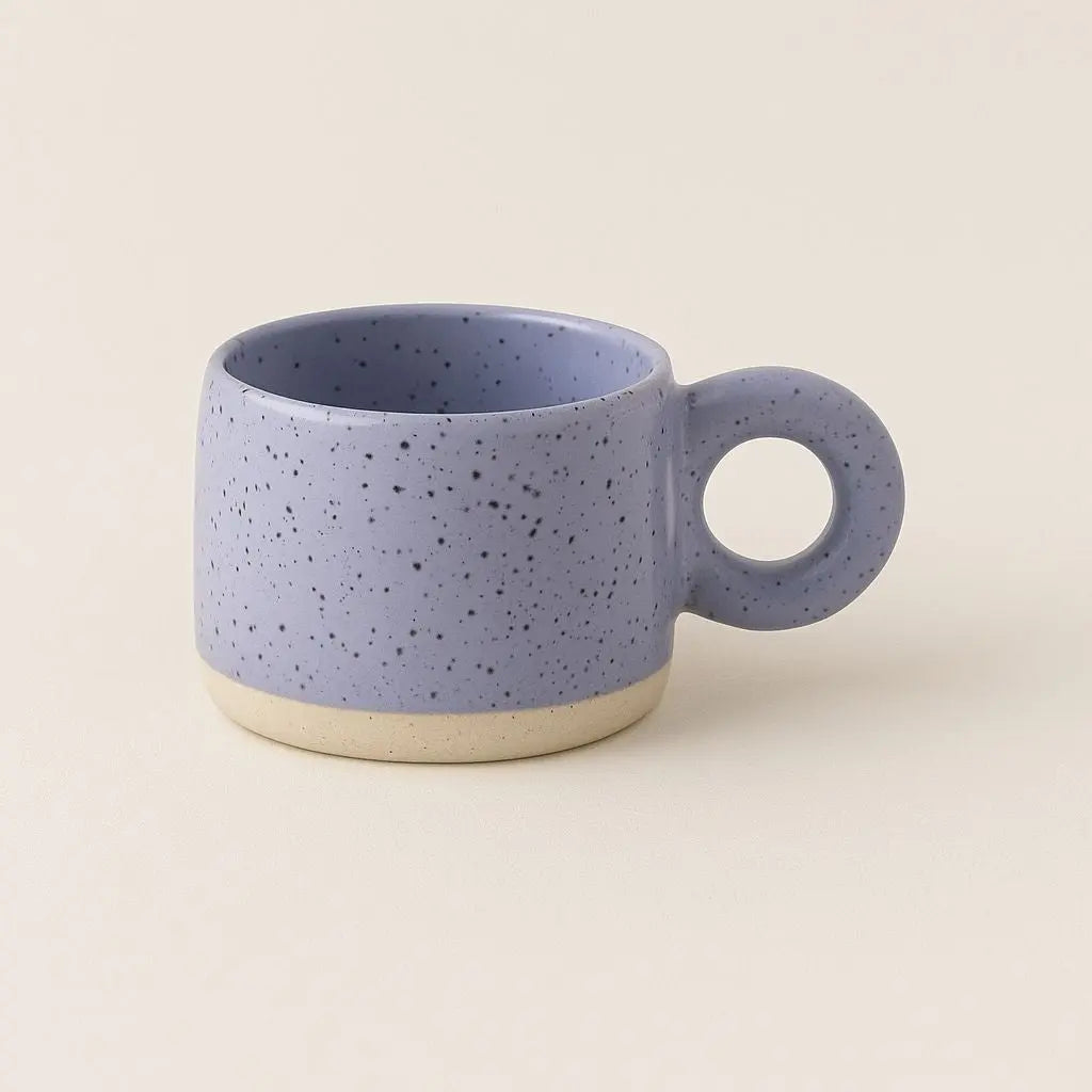 Ceramic coffee mug featuring distinctive circular handle and speckled texture for comfortable grip