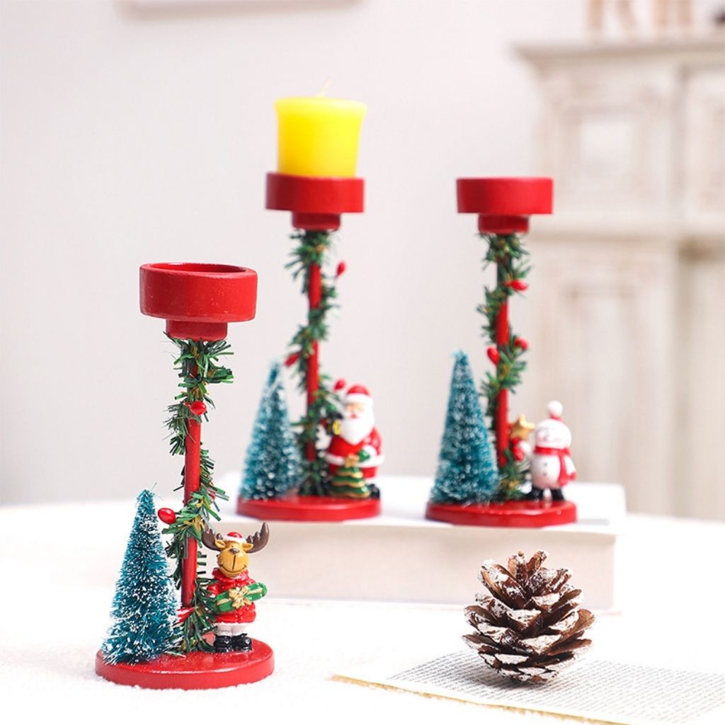 Festive candle holder with winter figurine and tree detail on white resin pedestal