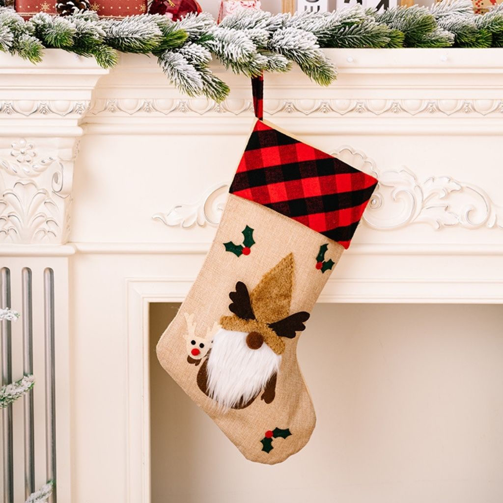 Christmas stocking with reindeer design hanging on a fireplace mantle.