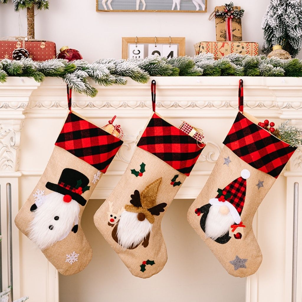 Three Christmas stockings with festive designs hanging on a fireplace mantle.