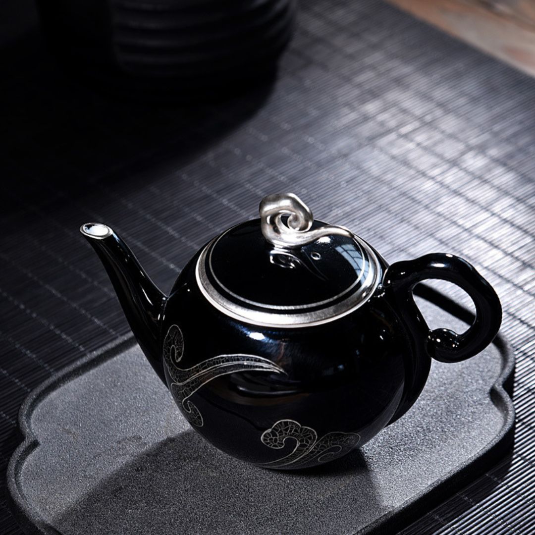 Handcrafted black glazed ceramic teapot with decorative silver detailing for tea ceremony
