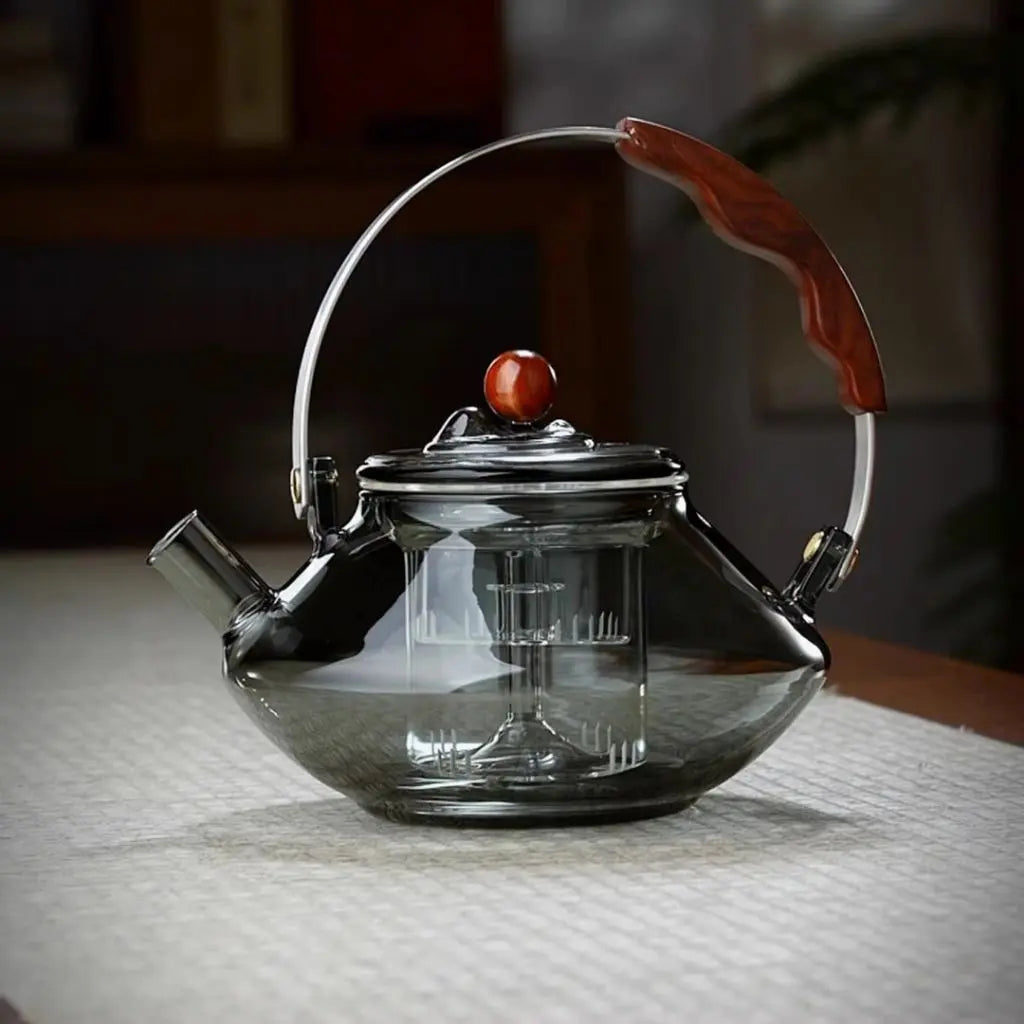 Clear glass teapot with a wooden knob on a textured surface