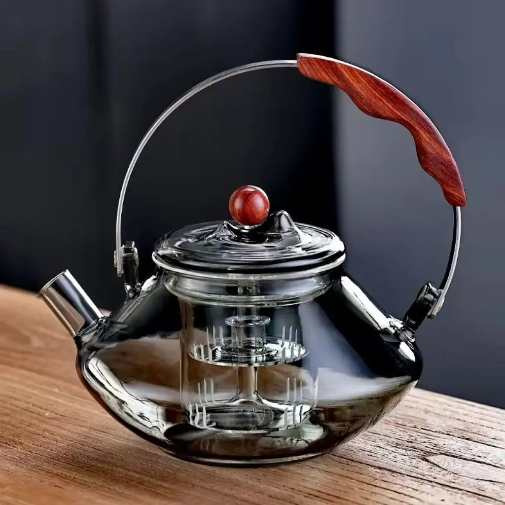 Clear glass teapot with wooden handle on a wooden surface