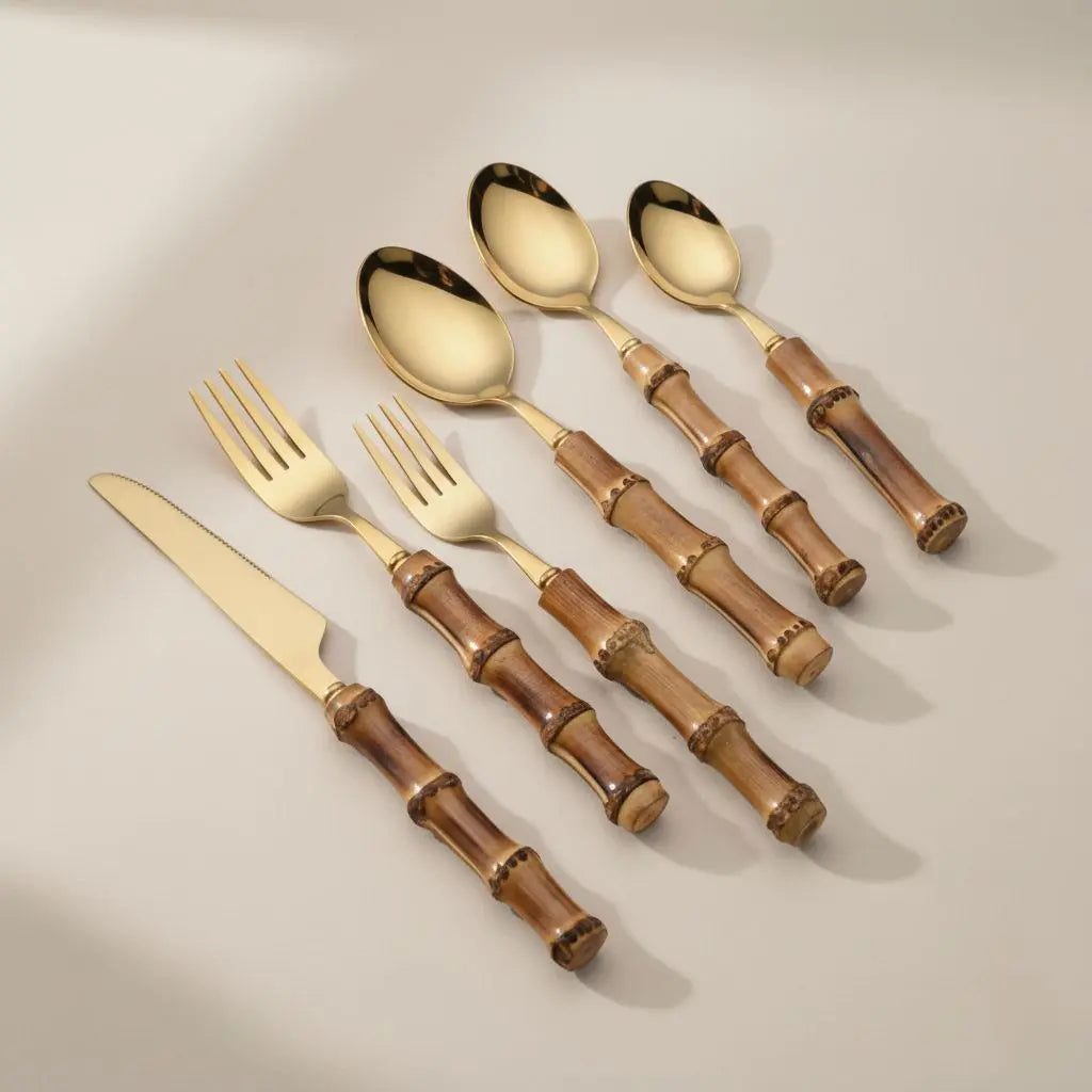 Set of gold cutlery with brown bamboo handles on a beige background