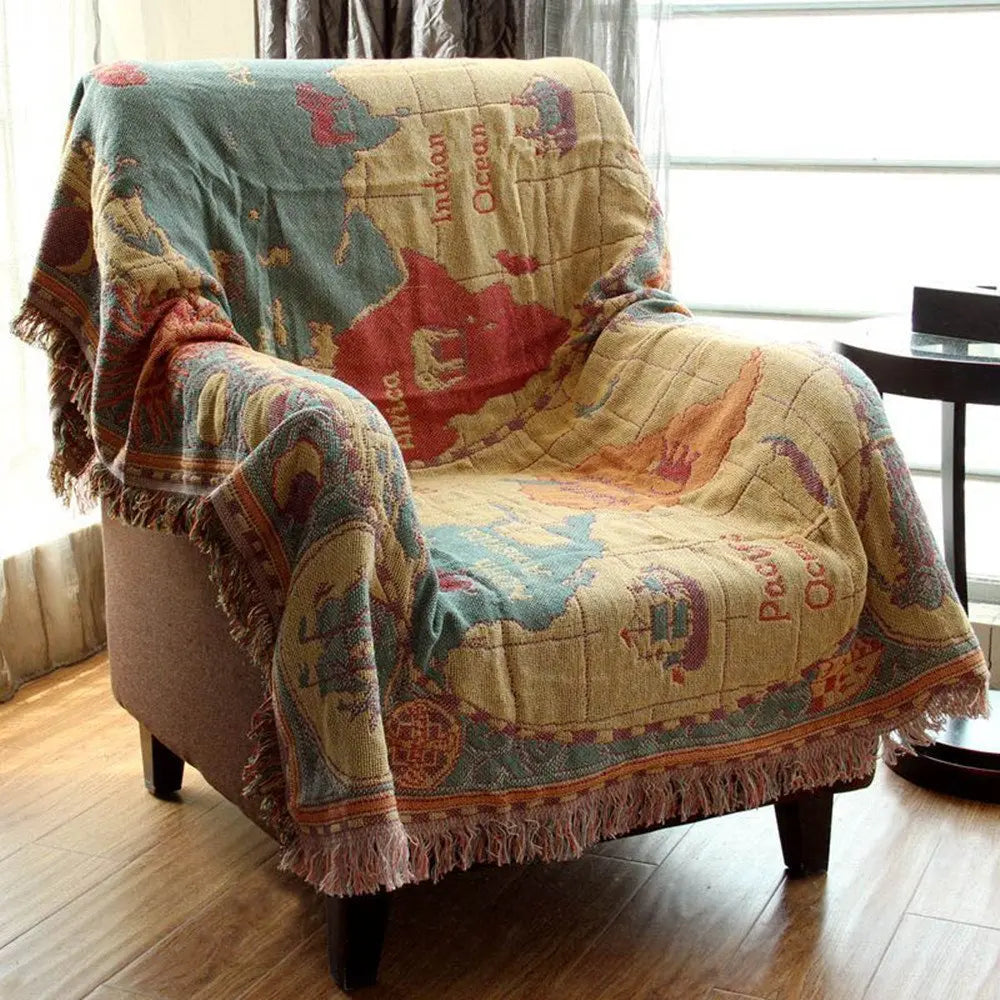 Map-themed blanket draped over a chair in a room with a window and table.