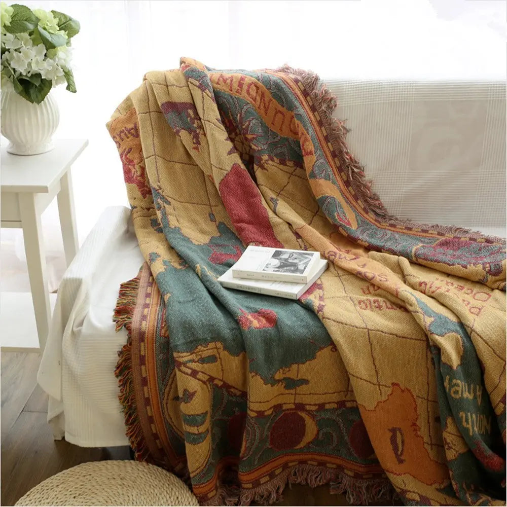 Decorative blanket with world map design draped over a sofa in a living room.