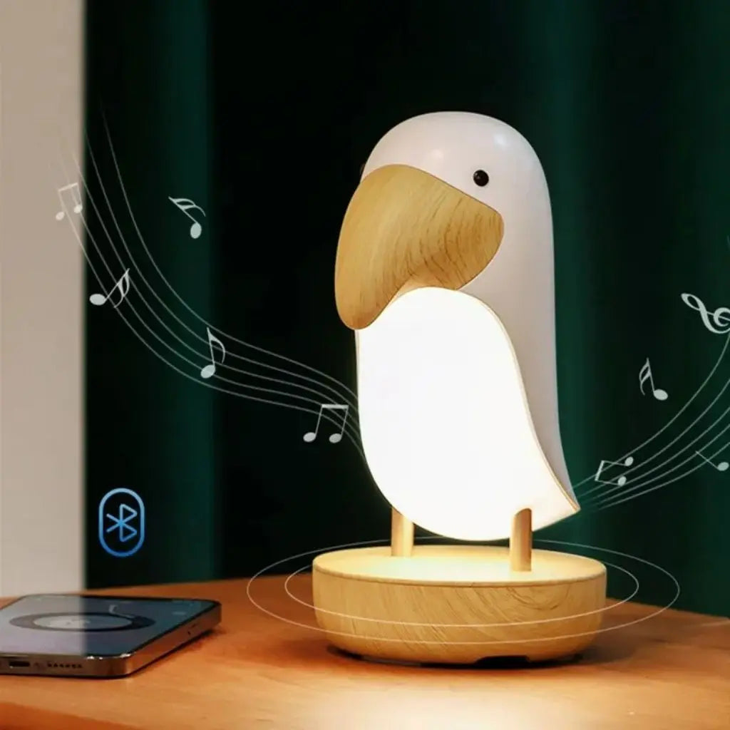 Bird-shaped lamp with Bluetooth symbol on a wooden base, next to a smartphone on a dark background.