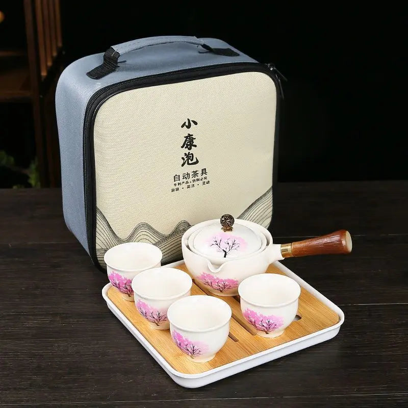 Tea set with pink floral design on a wooden tray in front of a carrying case.