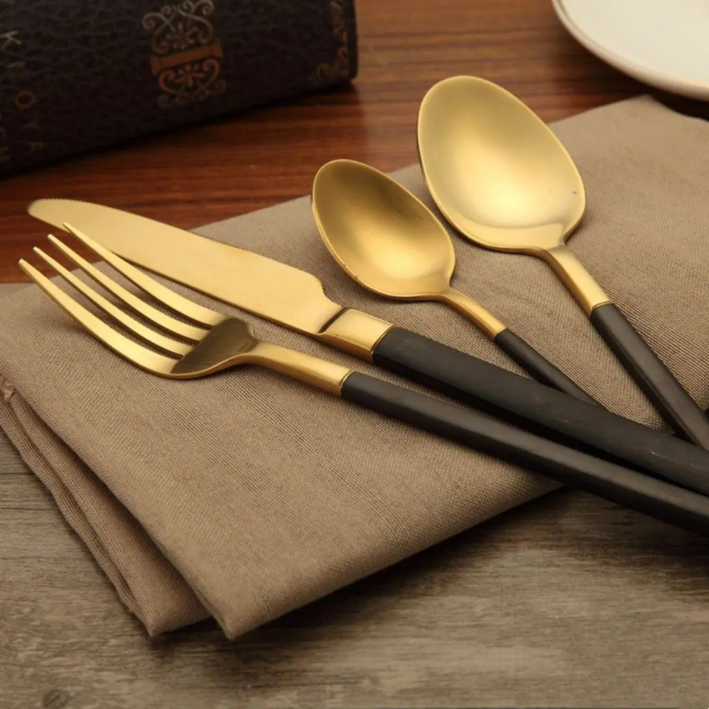 Modern gold cutlery set with matte black grips, complete flatware service for everyday dining