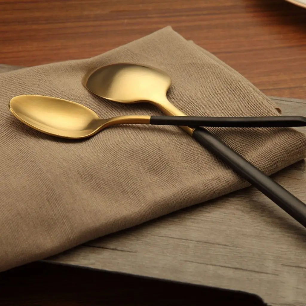 Brushed gold dining flatware with ergonomic black handles, ideal for meal service and table settings