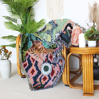 Colorful patterned blanket draped over a chair in a room with plants and decor.