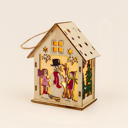 Decorative wooden house-shaped lantern with a snowman design, surrounded by green gift boxes.